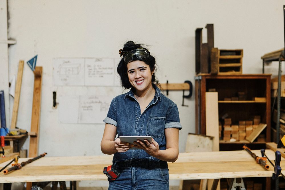 Cheerful female carpenter using a tablet in her workshop
