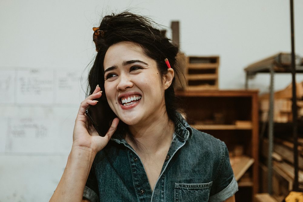 Cheerful female carpenter talking on a phone