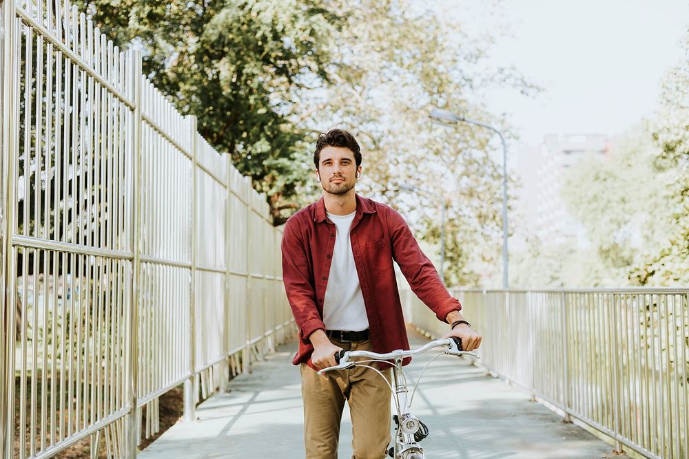 One caucasian man pushing his bicycle at park