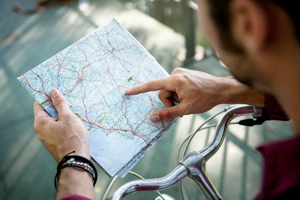 Cyclist checking and pointing on a map