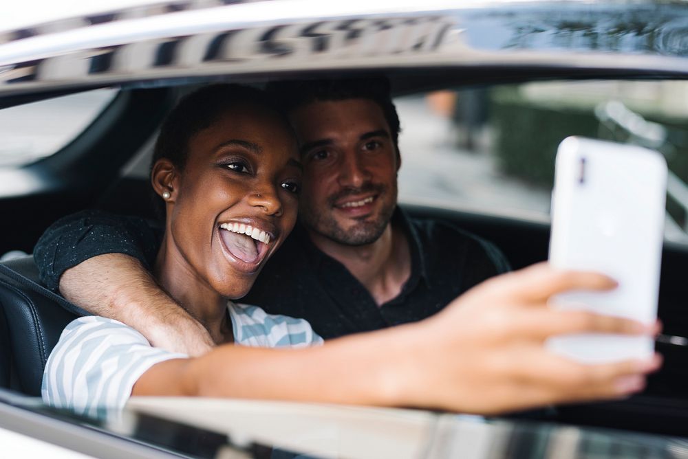 Happy and loving couple taking a selfie in a car