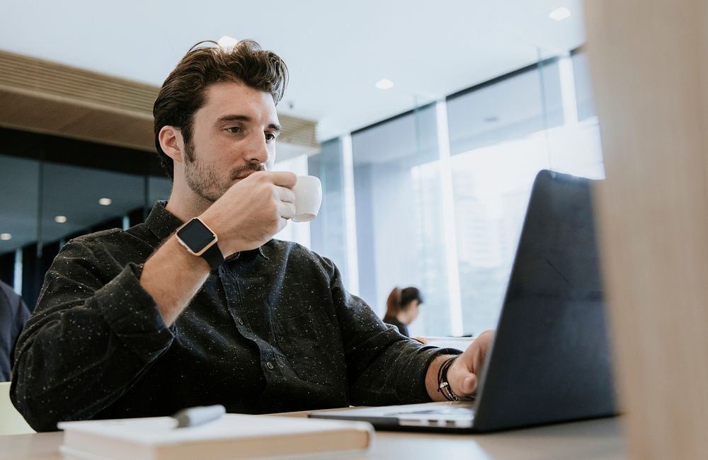 Man sipping coffee while working
