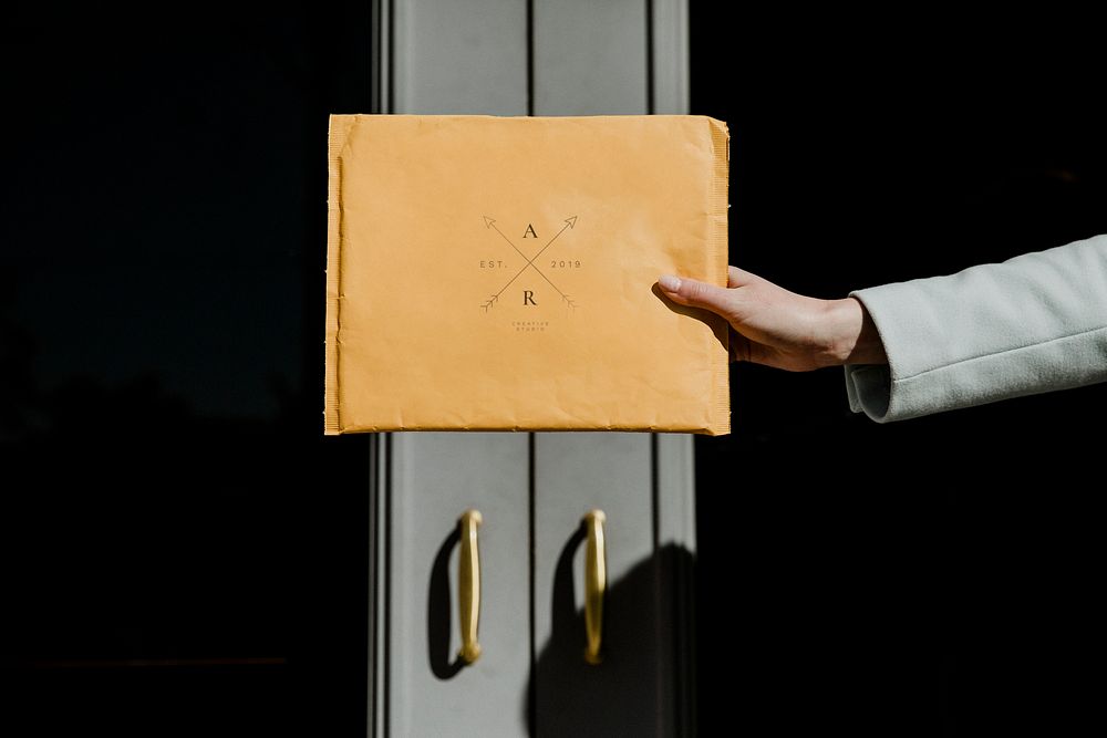 Woman holding a brown envelope mockup in front of a building