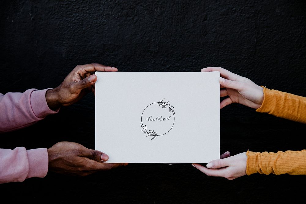Diverse hands holding a mockup card with "hello" text on a black background
