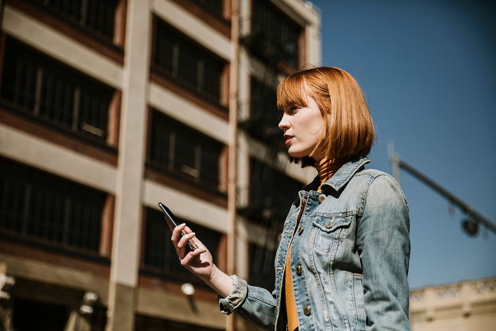 Woman standing on a streetside with her phone