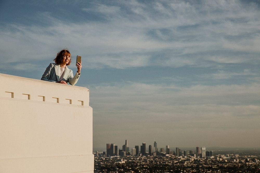 Woman capturing the Los Angeles view with her phone at the Griffith Observatory, USA