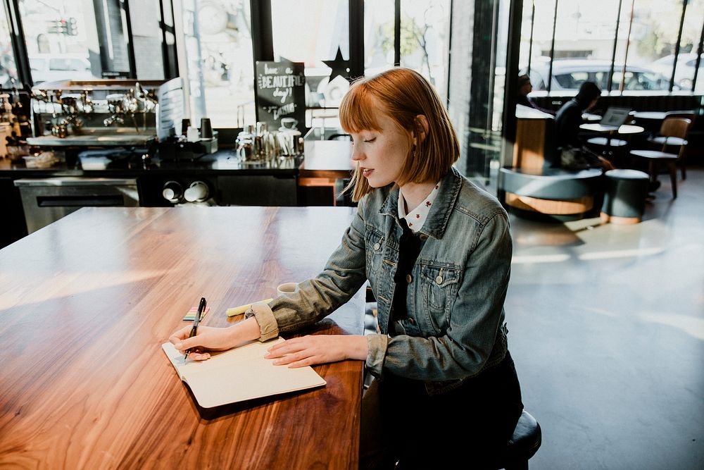 Woman writing on her notebook in a cafe