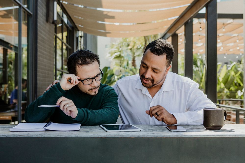 Business partners using digital devices in a cafe