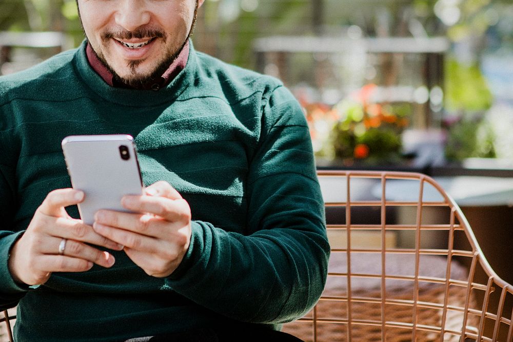 Happy man using a smartphone in a cafe