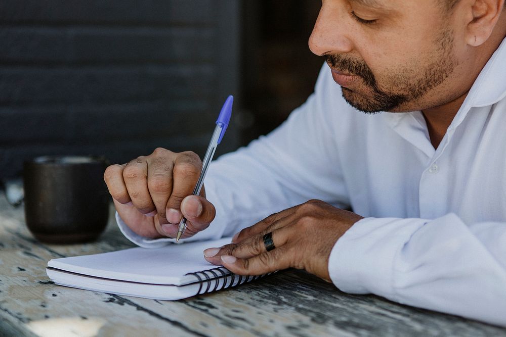 Businessman writing in a notebook in a cafe