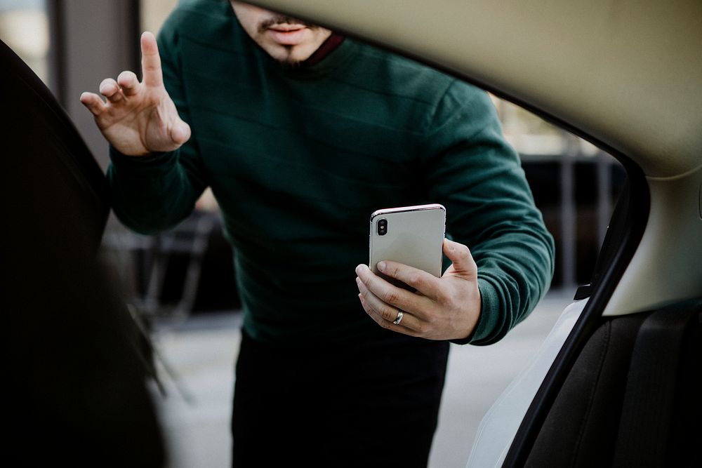 Man with his mobile phone entering a car