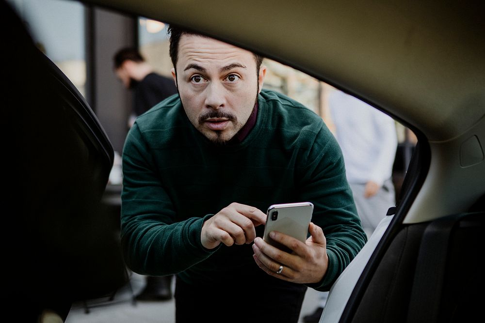 Man with his mobile phone entering a car