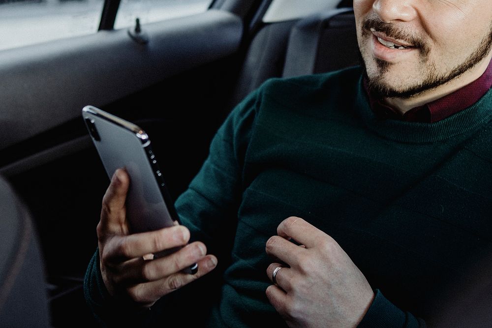 Happy man using his smartphone in the car
