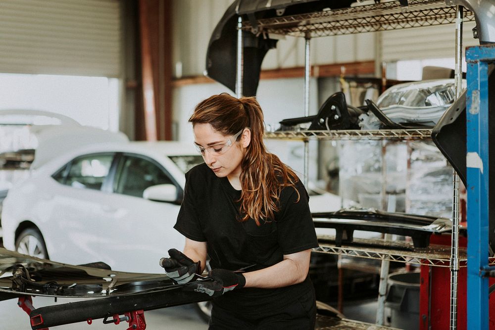 Female technician fixing car parts in a garage