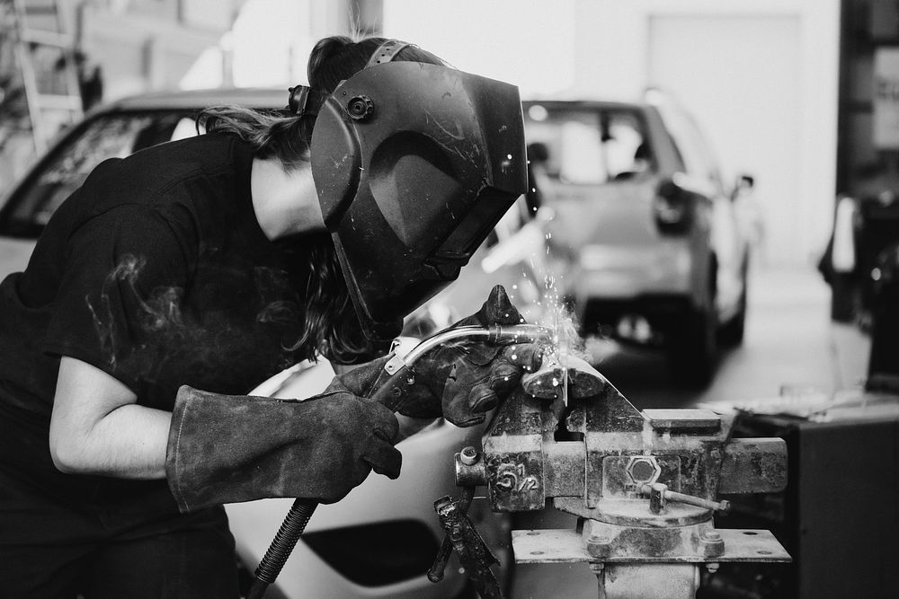 Female welding a metal piece in the garage