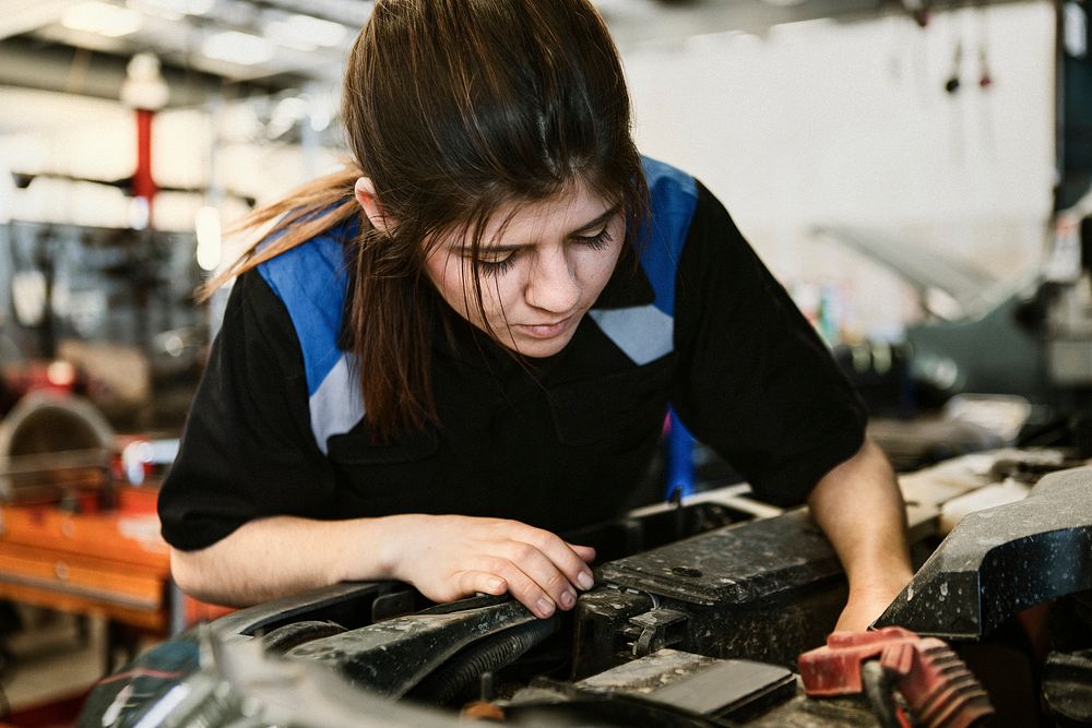 Female mechanic checking under the hood of a car