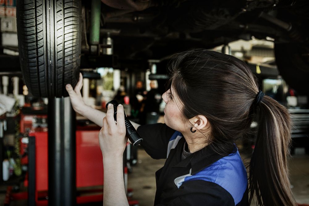 Female mechanic observing the car tire
