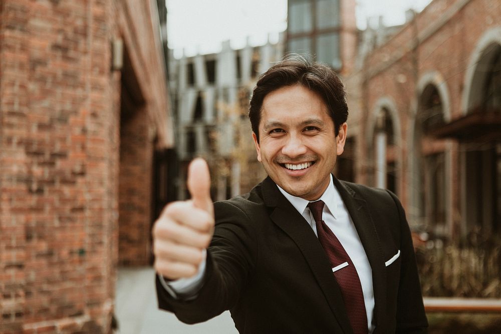 Happy businessman doing a thumbs up in the city