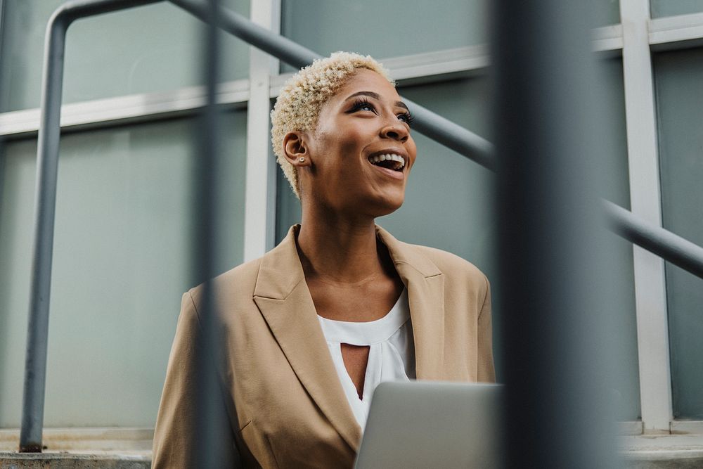 Happy businesswoman sitting on the steps with her laptop