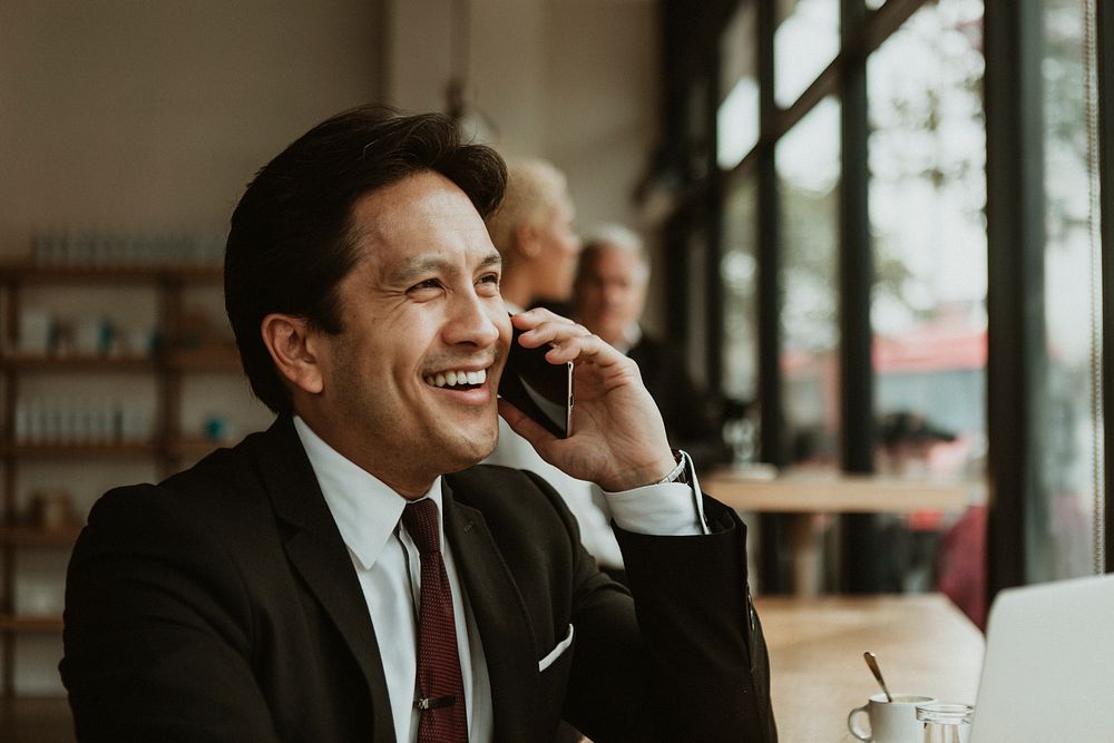 Happy businessman on the phone in a cafe