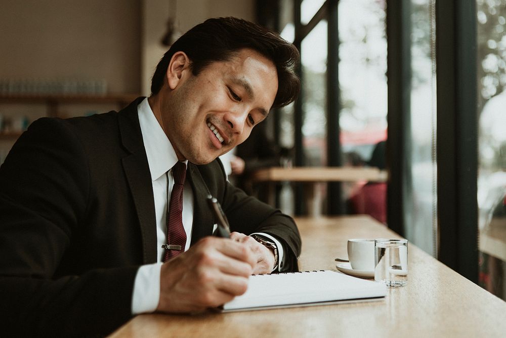 Happy businessman writing in a cafe