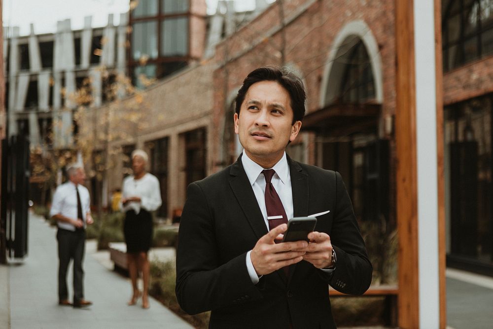 Businessman using his smartphone while walking in the city