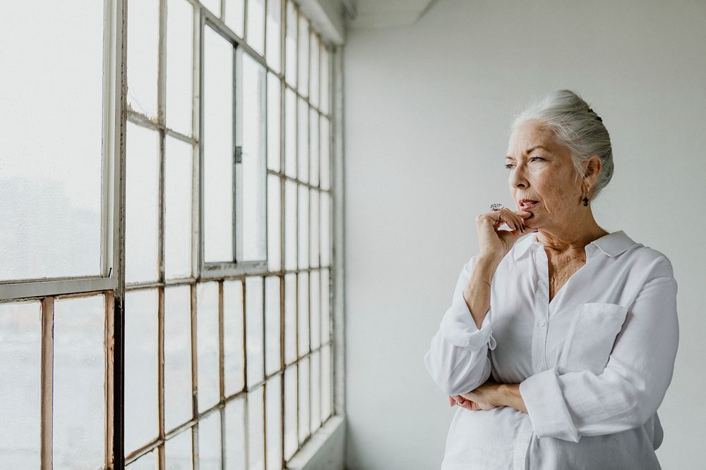 Thoughtful senior woman looking through the window