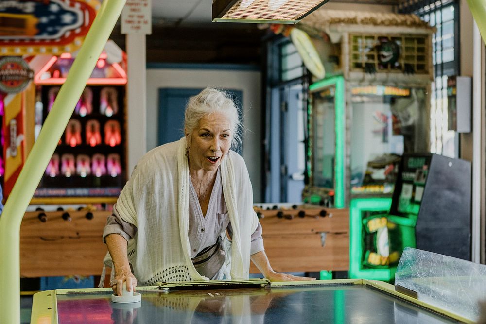 Happy senior woman playing table hockey at the arcade
