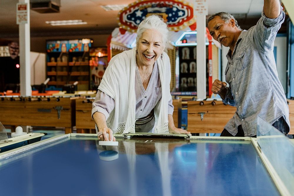 Happy senior couple enjoying a game of table hockey inside of a game arcade