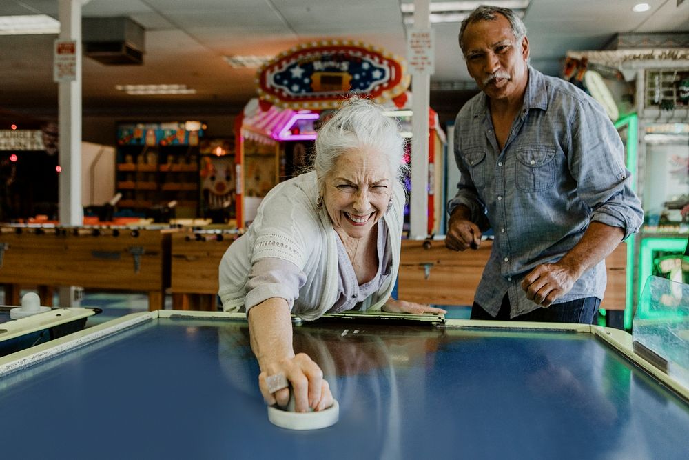 Happy senior couple enjoying a game of table hockey inside of a game arcade