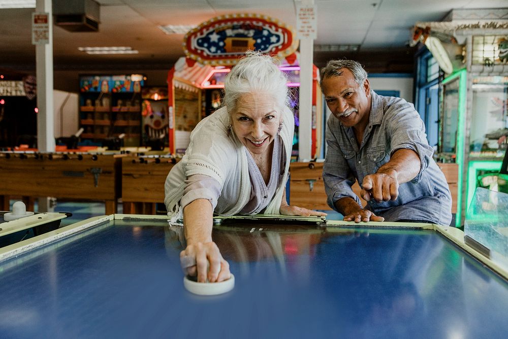 Happy senior couple enjoying a game of table hockey inside of a game arcade