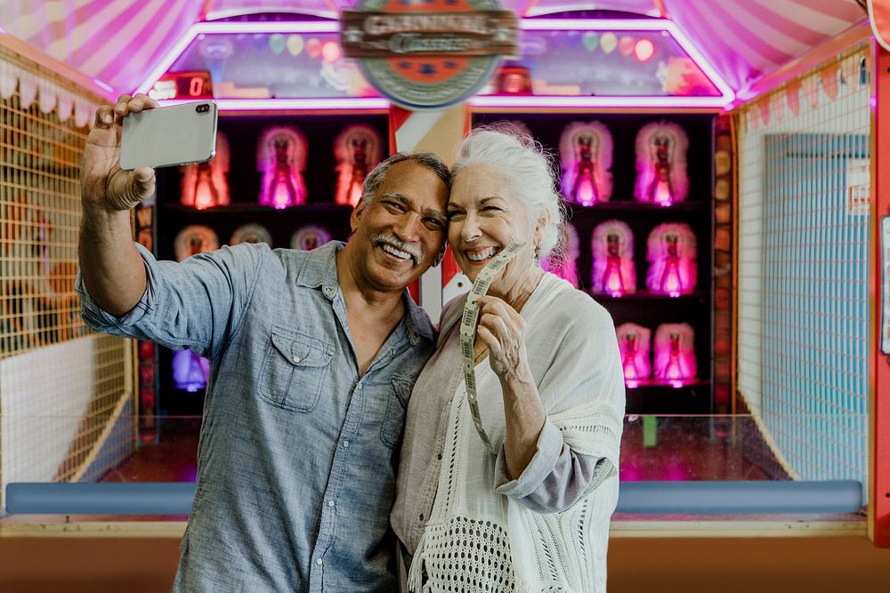 Happy senior couple taking a selfie with raffle tickets