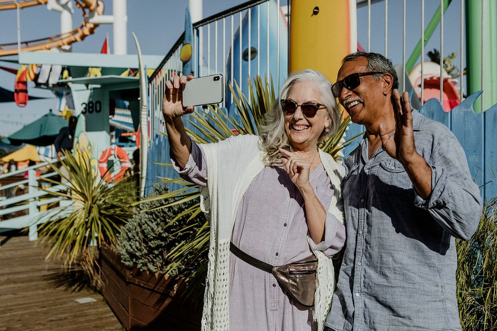 Cute senior couple taking a selfie at an amusement park