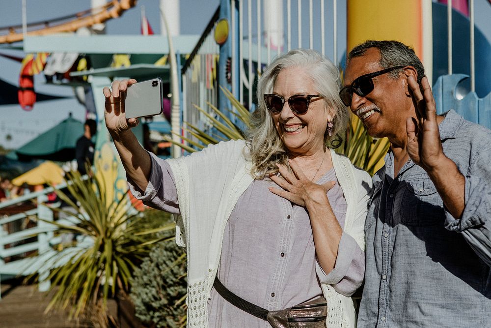 Cute senior couple taking a selfie at an amusement park
