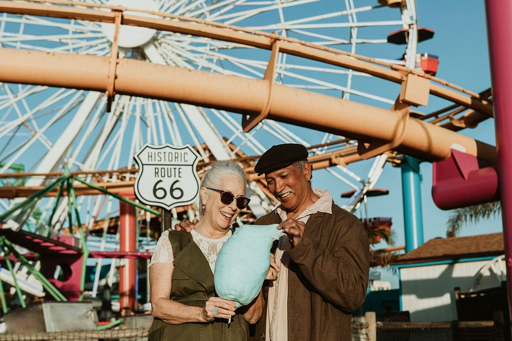 Cheerful elderly couple enjoying cotton candy at Pacific Park in Santa Monica, California