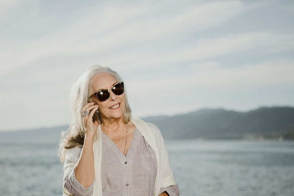 Senior woman talking on the phone by the sea