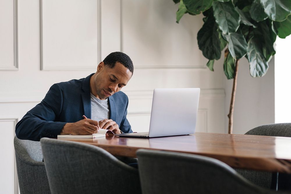 Casual businessman writing on his agenda next to a laptop