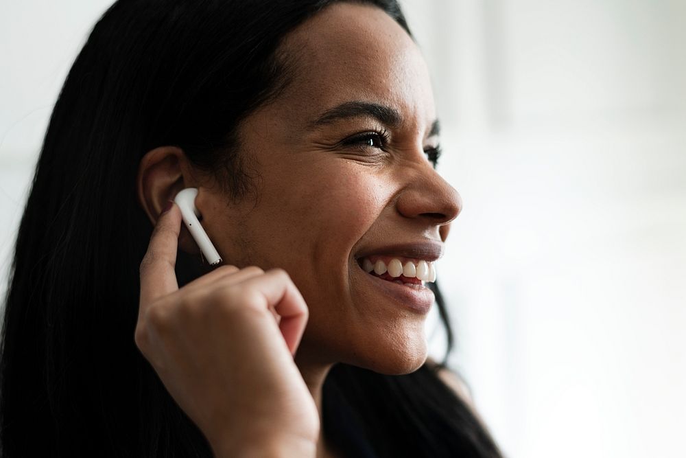 Cheerful woman enjoying music through a wireless earphone