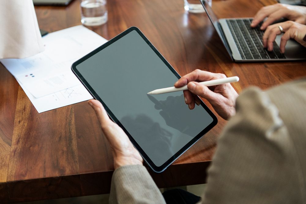 Business person using a wireless stylus with a digital tablet mockup in a meeting