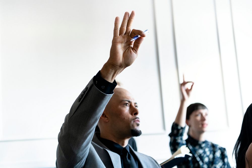 Business people in a seminar raising their hands