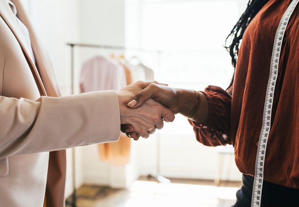 Two women shaking hands in a boutique