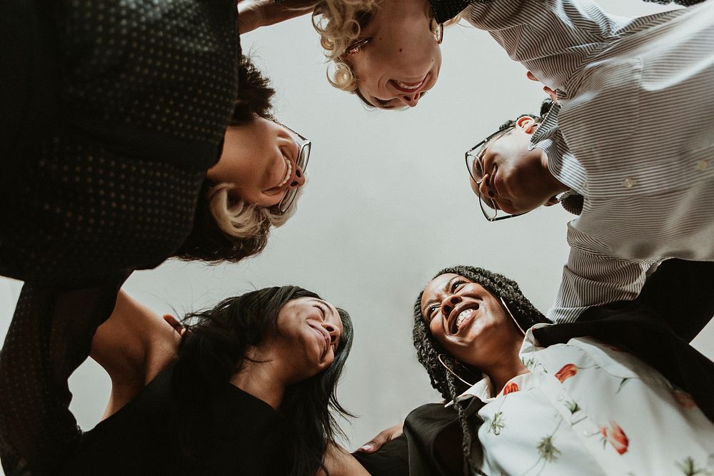 Happy diverse businesswomen huddling in the office