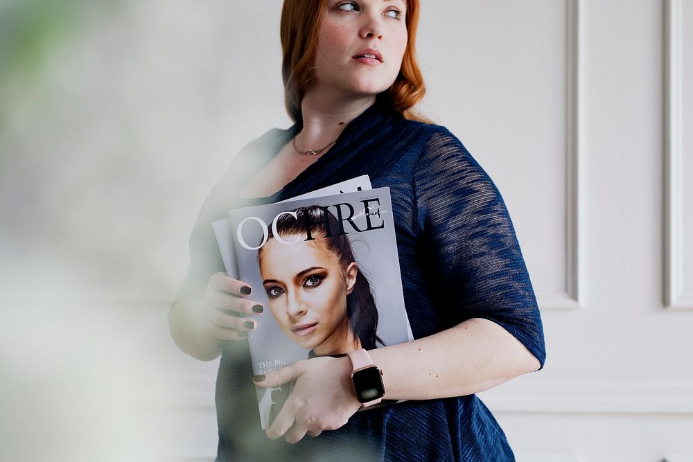 Woman wearing a smartwatch and holding a magazine