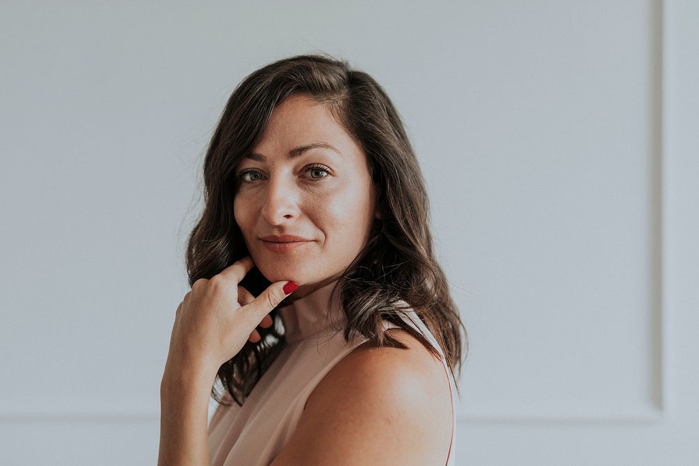 Happy woman standing by a white wall