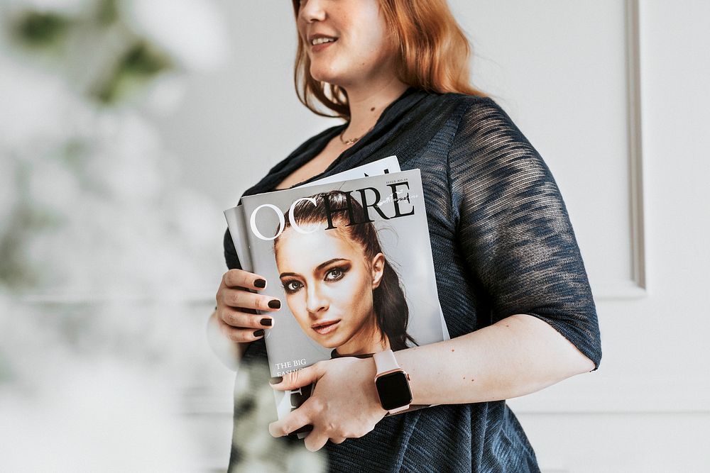 Woman wearing a smartwatch and holding a magazine