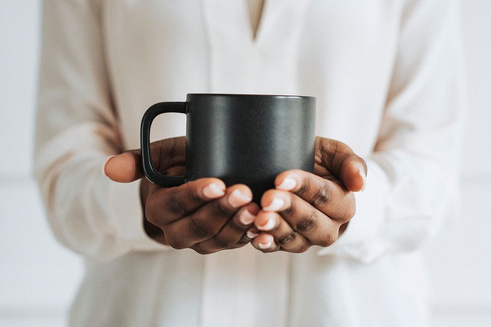 Hands holding a black cup of coffee