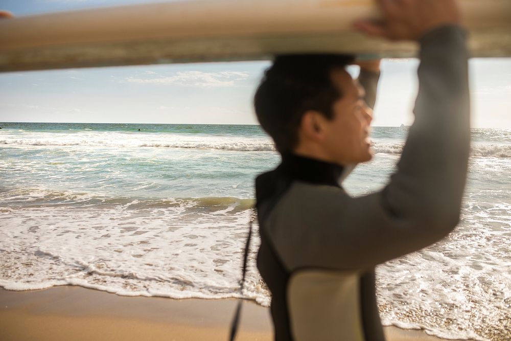 Surfer carrying a surfboard at the beach