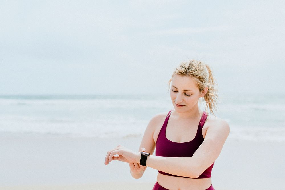 Sporty woman checking her smartwatch on the beach