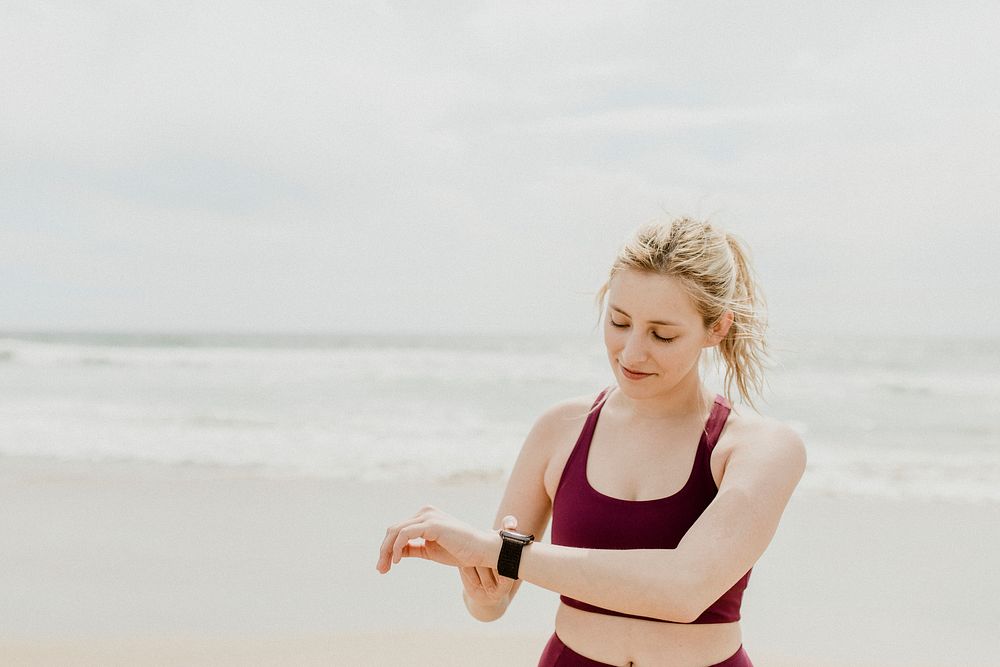 Sporty woman checking her smartwatch on the beach