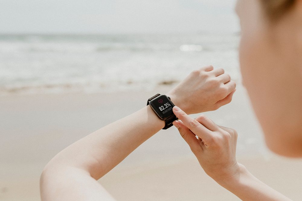 Woman checking her smartwatch on the beach